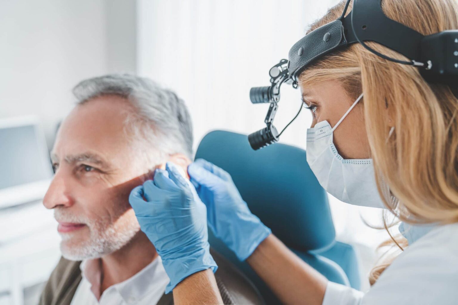 Man with hearing problem having his ears examined by a medical professional.