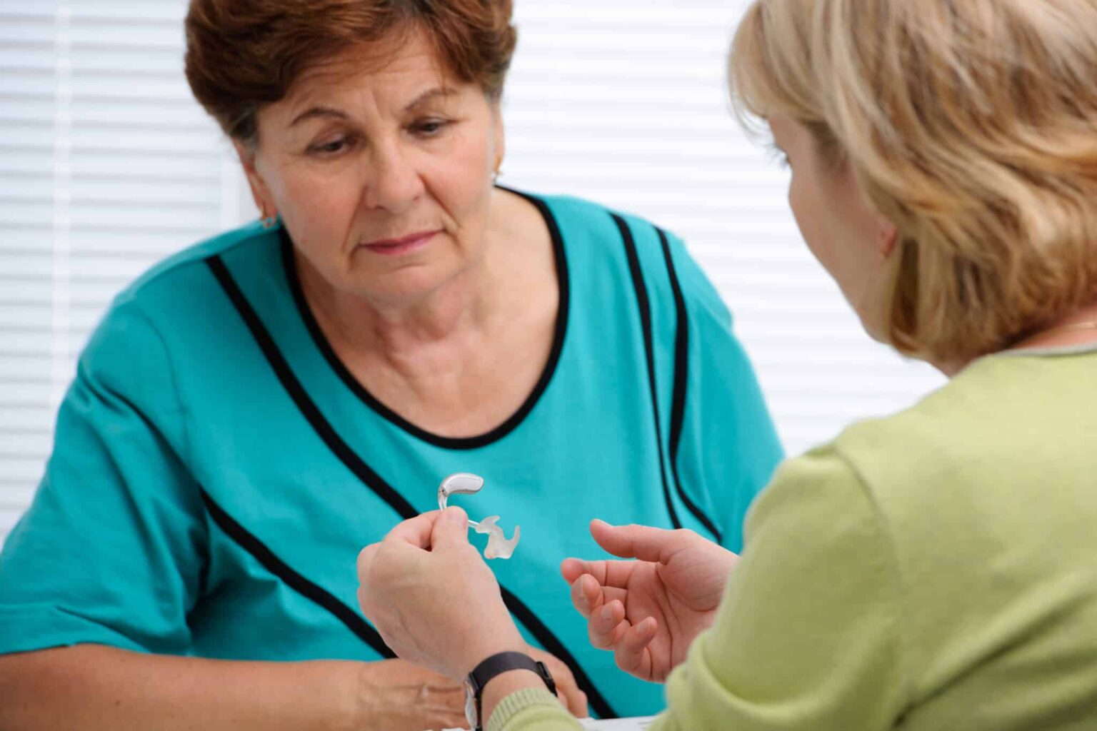 Audiologist explaining how hearing aids work to a patient.