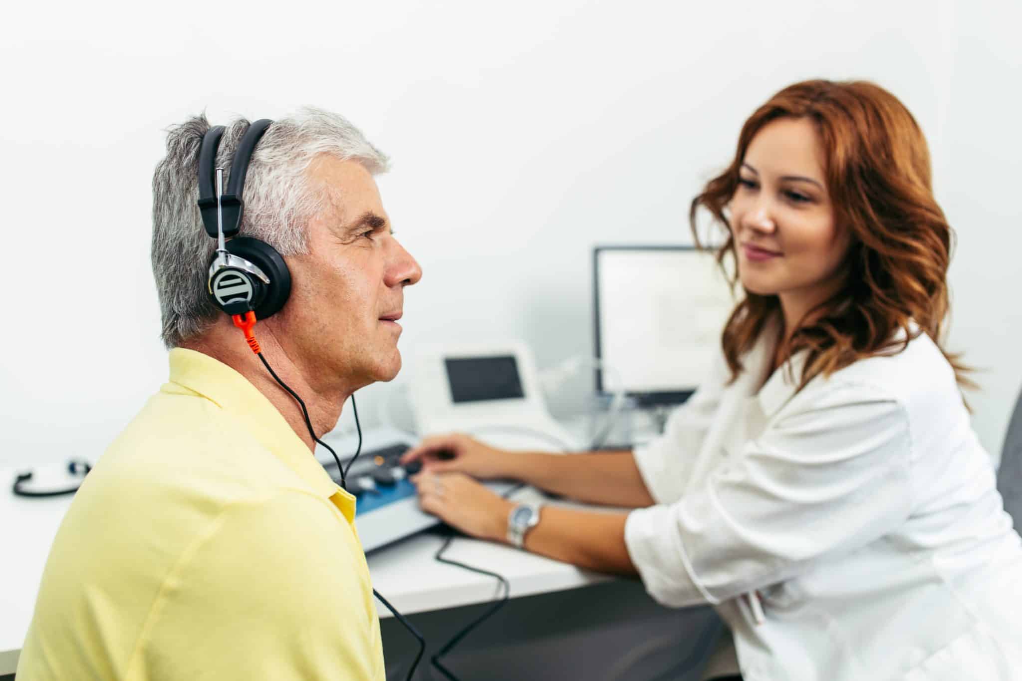 Patient with headphones on gets tested for hearing loss by a hearing care provider