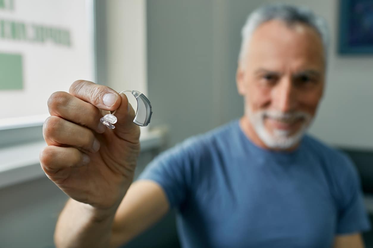 Senior man holding up his BTE hearing aid.