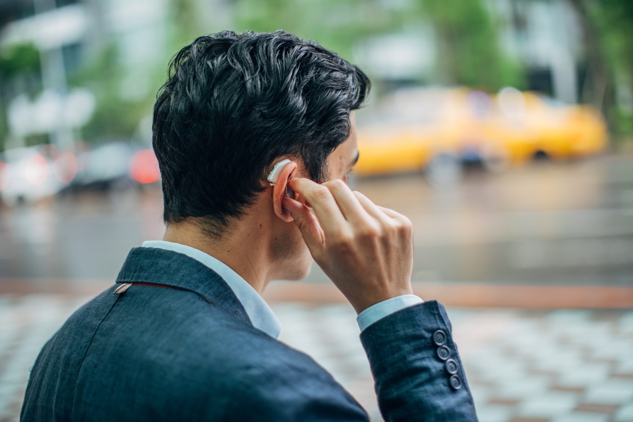 Man touches behind the ear hearing aid