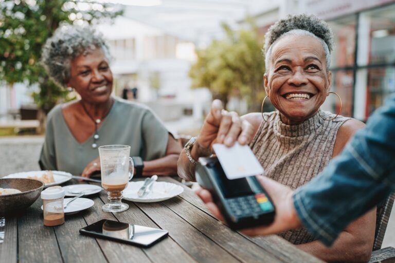 Senior woman making credit card payment Senior woman and her friend paying for dinner at a restaurant