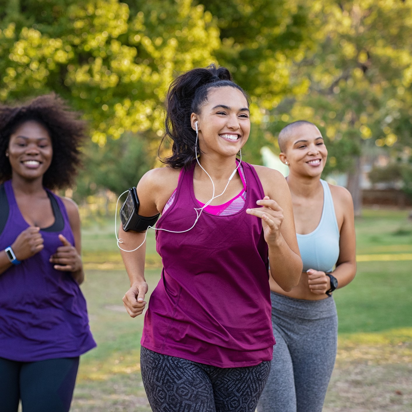 Group of smiling friends running outdoors.