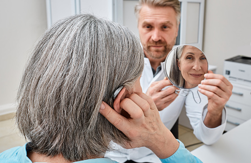 Audiologist and patient fine-tune a new pair of hearing aids to customize them to the patient's needs.