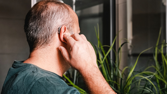 Behind view of a man adjusting his hearing aid